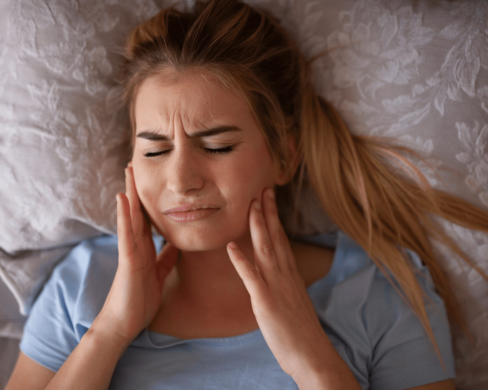 Woman clutching jaw, eyes closed