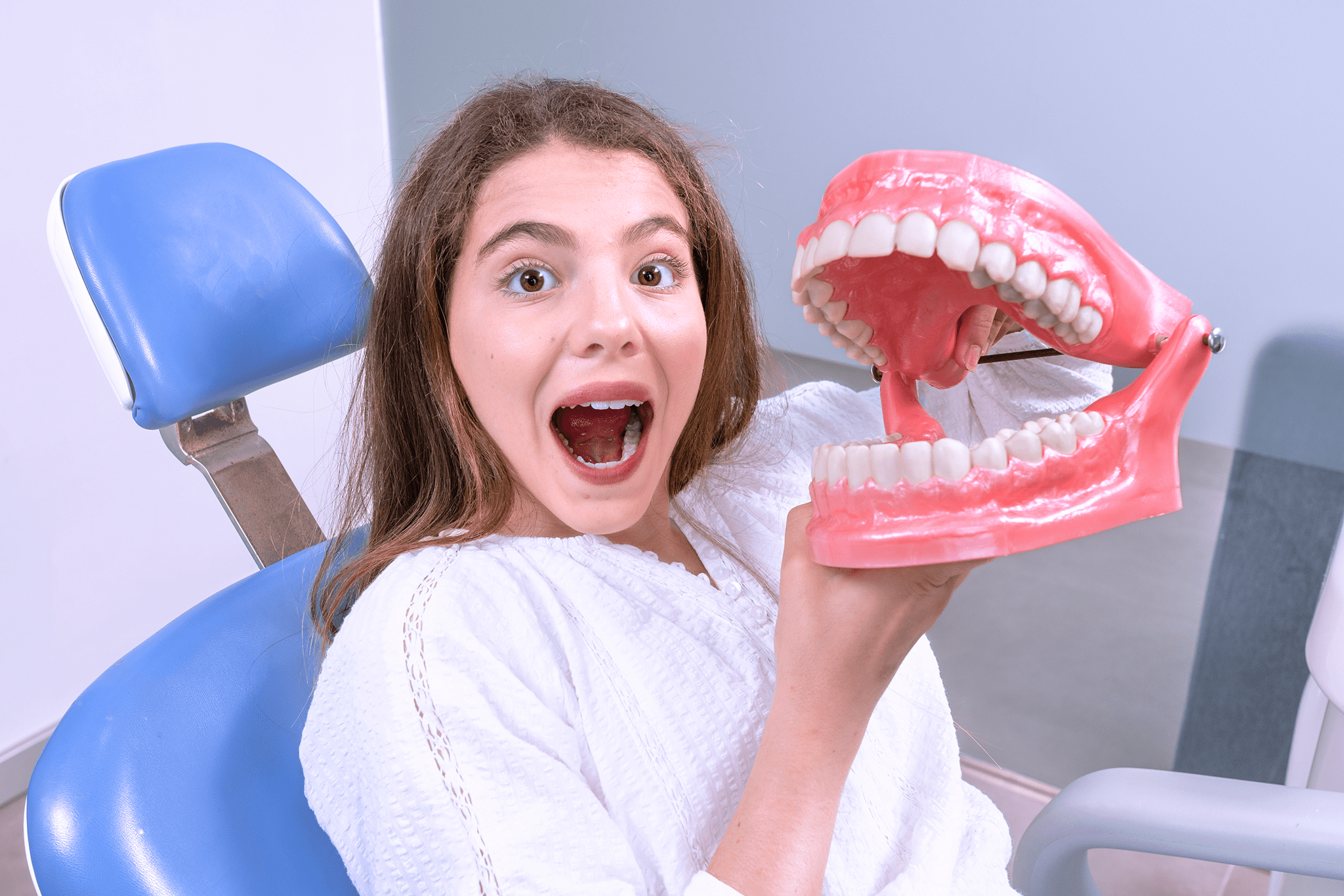 Surprised girl holding oversized dental model